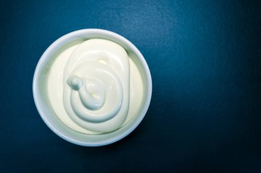 Siyah arka planda beyaz tabakta mayonez sosu.