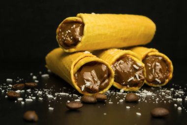Siyah zemin üzerinde yoğunlaştırılmış süt ile waffle ruloları