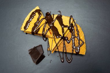 Yoğunlaştırılmış sütle waffle ruloları, siyah arka planda çikolatayla sulandırılmış.