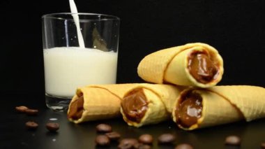 Waffle tüplerinin yanında bir bardak süt var.