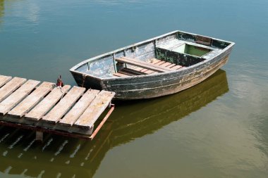 Duvarın yanındaki nehirde eski ahşap bir tekne.