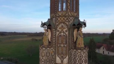 close aerial drone view flying around a chapel in a small village in france stone angels decoration sunset time