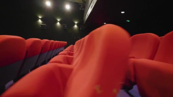 空の映画館にある赤い映画館のアームチェアの横からの眺めスローモーションを左にスムーズに撮影 — ストック動画