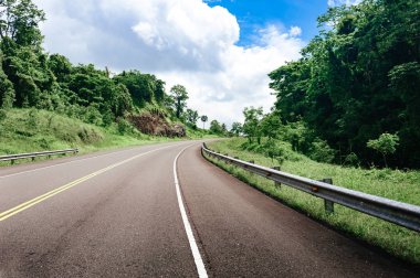 yol geçiş orman ve tepeler ile bulutlu gökyüzü arka plan üzerinde  