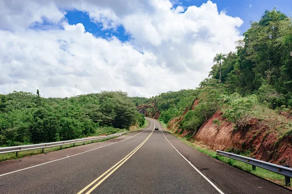 road crossing forest and hills with cloudy sky on background