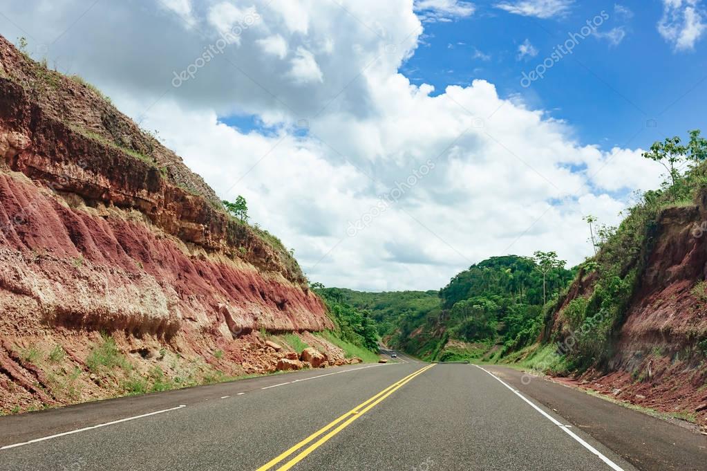 road crossing forest and hills with cloudy sky on background  