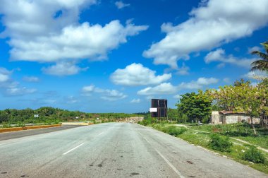 Palmiye ağaçları mavi gökyüzü ve bulut karşı olan güzel asfalt yol. Karayolu tropik ada üzerinde. Öğleden sonra sahil yolu. Boş yol deniz tarafından. Yeşil tepe, plaj, coco palmiye ağacı üzerinde yol kenarında. Orman ve deniz manzara. Yaz tatil seyahat 