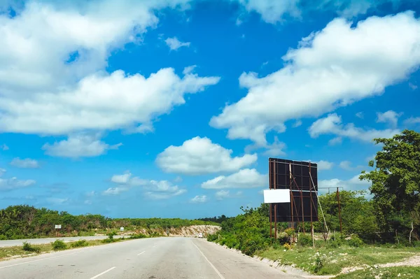 Nice asfalt road with palm trees against the blue sky and cloud. Highway on tropical island. Coastal road in the afternoon. Empty road by the seaside. Green hill, beach, coco palm tree on the roadside. Forest and sea landscape. Summer holiday travel