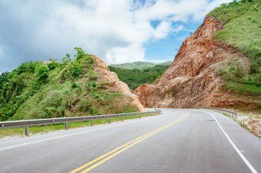 Bulutlu gökyüzü ve dağ manzaralı ormanı geçerken yol.