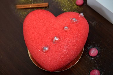 Sevgililer, yıldönümleri ve doğum günü için kalp şeklinde kırmızı bir pasta. Sevgililer günü için süslemeler ile cupcakes