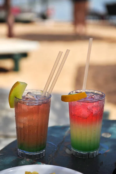 Zwei bunte Cocktails auf dem Hintergrund des Strandes. zwei Gläser mit buntem Cocktail an einem Strand in der Nähe des Ozeans. — Stockfoto