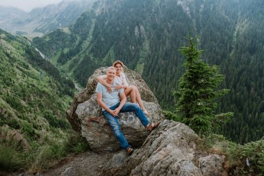 Genç ve tatlı bir çift balayı kayalara oturup poz verir ve ellerini tutarlar. Güzel bir yerde, İtalya 'da, okyanus ve dağlara yakın bir yerde, kucaklaşır, gülümser ve konuşurlar.