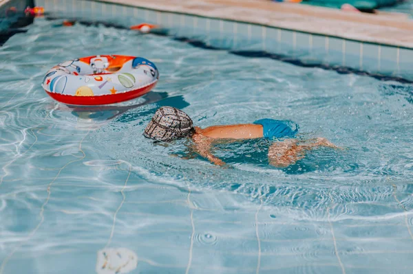 Счастливый мальчик плавает и ныряет под воду, ребенок мажет грудь с весельем в бассейне. Активный здоровый образ жизни, занятия водными видами спорта и занятия с родителями на летнем семейном отдыхе с ребенком. — стоковое фото
