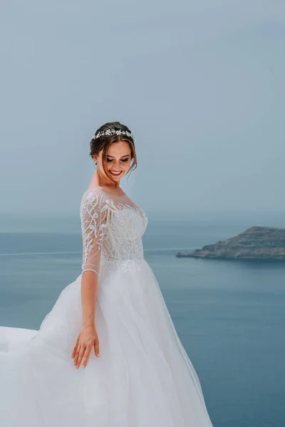 Romantická krásná nevěsta v bílých šatech pózuje na terase s mořem a horami v pozadí — Stock fotografie