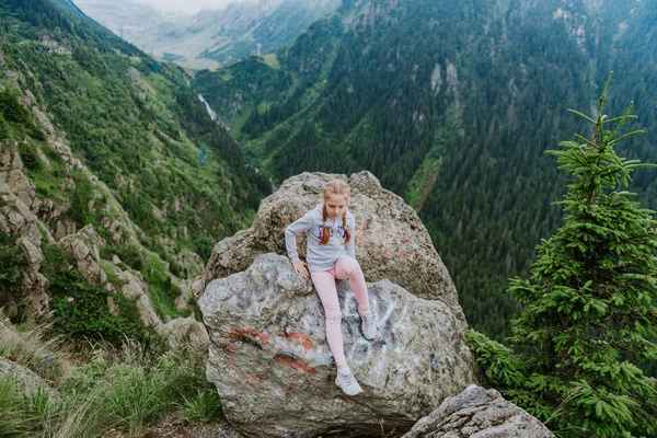 小女孩坐在岩石上 身后有山 — 图库照片