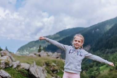 Genç kız dağlarda poz veriyor.