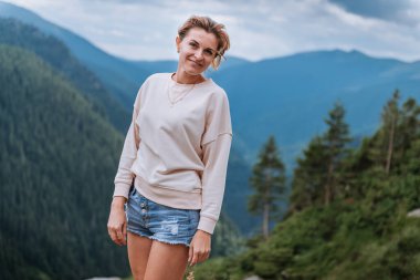 Genç bir kadın uçurumun kenarında duruyor ve gökyüzüne bakıyor..