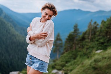 Genç bir kadın uçurumun kenarında duruyor ve gökyüzüne bakıyor..