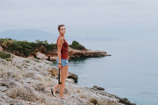 Un verano perfecto. Retrato de mujer sonriente en pantalones cortos y blusa roja con bolsa de playa blanca en la playa tomando selfie usando selfie stick — Foto de Stock