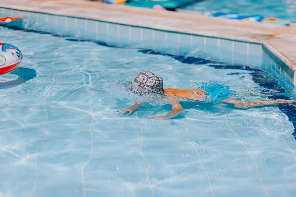 Счастливый мальчик плавает и ныряет под воду, ребенок мажет грудь с весельем в бассейне. Активный здоровый образ жизни, занятия водными видами спорта и занятия с родителями на летнем семейном отдыхе с ребенком. — стоковое фото