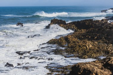 Sahilde ve sahilde kayaları vuran deniz dalgaları.