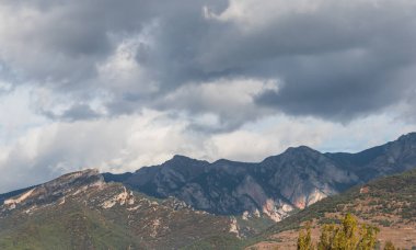 Gün boyunca bulutlarla çevrili dağların manzarası