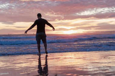 Genç atletik çocuk sahilde yürüyor.