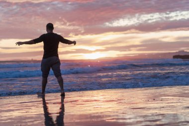 Genç atletik çocuk sahilde yürüyor.