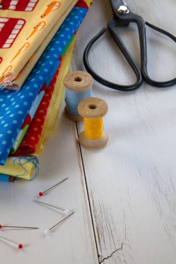 Vintage renkli kumaşlarla makas, iğne, teyp ölçme ve pamuk konuları Beyaz ahşap masa üzerinde haddeleme