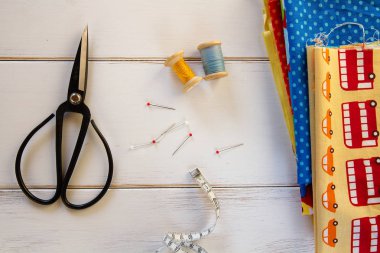 Vintage renkli kumaşlarla makas, iğne, teyp ölçme ve pamuk konuları Beyaz ahşap masa üzerinde haddeleme