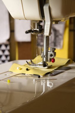 Dikiş makinesi ile sarı kumaş ve toplu iğneler