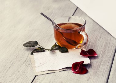 Teknik İncelemeler ve ahşap masa, Sevgililer günü kavramı üzerinde çay bardağı ile gül yaprakları  