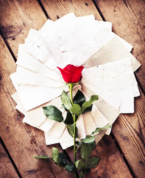 Rosa rosa con papeles sobre mesa de madera — Foto de Stock