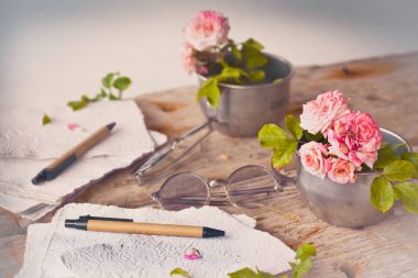 Pembe Gül retro gözlük ve beyaz el ile kağıt üzerinde ahşap masa arka plan yaptı. 