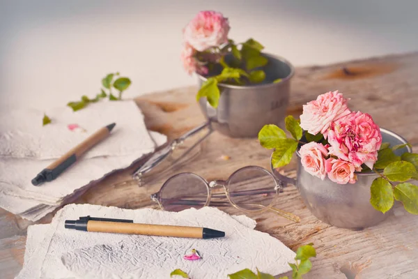 Pembe Gül retro gözlük ve beyaz el ile kağıt üzerinde ahşap masa arka plan yaptı. 