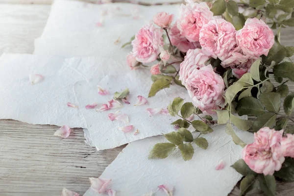 Růžové Růže Bílou Ruku Papír Pozadí Dřevěný Stůl — Stock fotografie