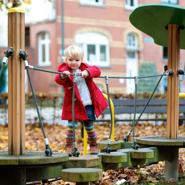 Активная маленькая девочка играет на детской площадке — стоковое фото