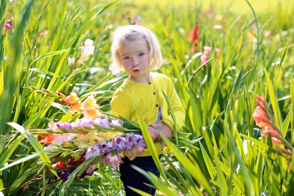 Mała dziewczynka zbierając kwiaty w polu — Zdjęcie stockowe