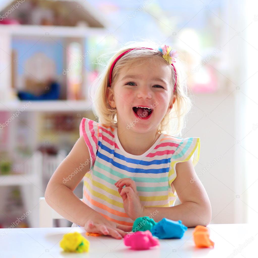 Preschooler girl playing indoors with plasticine