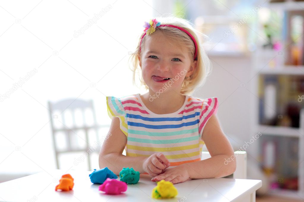 Preschooler girl playing indoors with plasticine