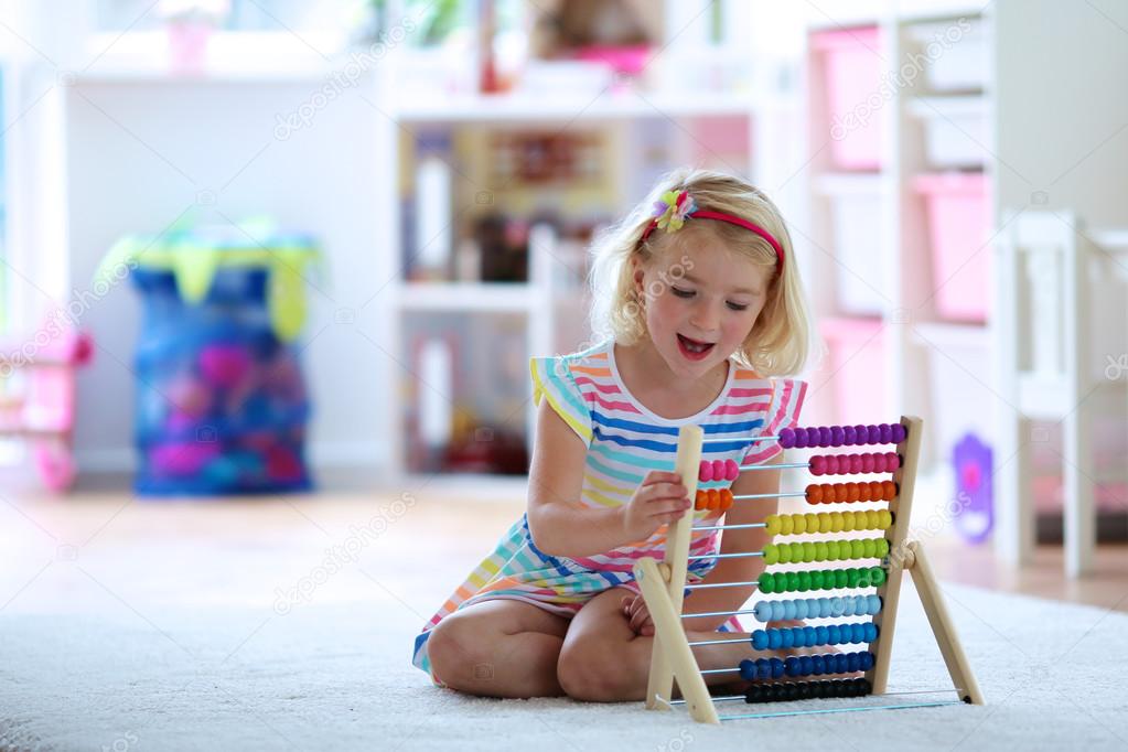 Preschooler girl playing with wooden toy abacus