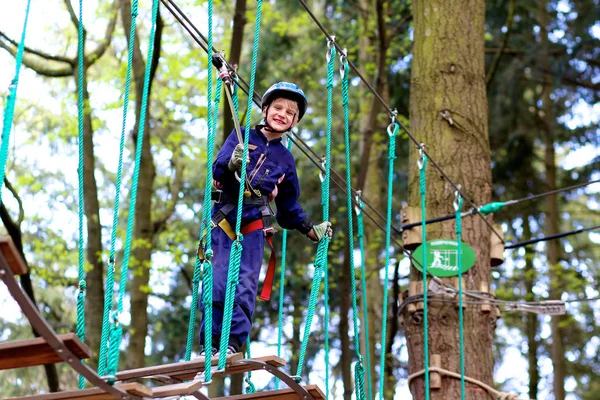 야외 모험 공원에 등반 하는 행복 한 소년 — 스톡 사진