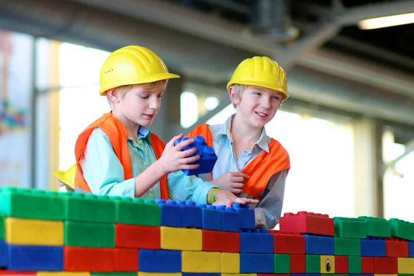 Two school boys playing with big building bricks — Stock Photo, Image