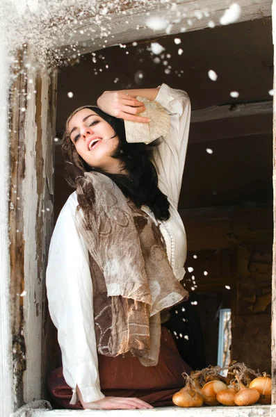 Gypsy woman with cards laughs looking out of the window under the snow