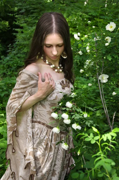 在布什公园白色玫瑰的复古礼服的女人 — 图库照片