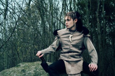 genç adam bir taş karanlık ormanın içinde oturan bir barbar kostüm