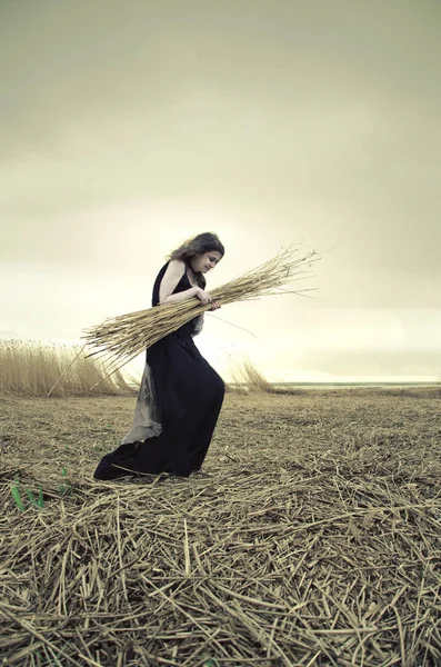 沼上茎を運ぶ葦に黒のドレスの若い女性の肖像画 — ストック写真