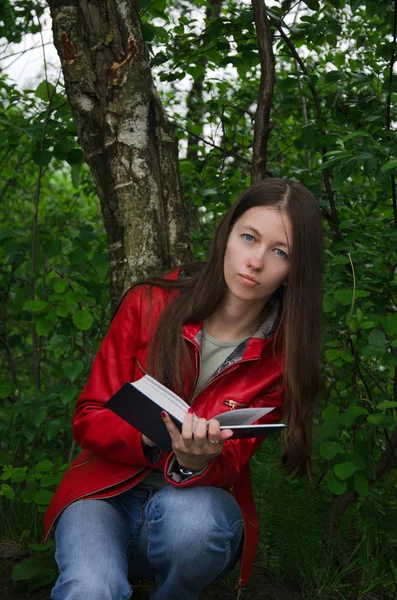 dark-haired student in a red jacket sitting in the Park near del