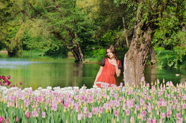 Žena v boho stylu chodí kolem velké pole tulipánů — Stock fotografie