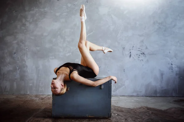 Young ballerina in a black dancing suit is posing in a loft studio — Stock Photo, Image